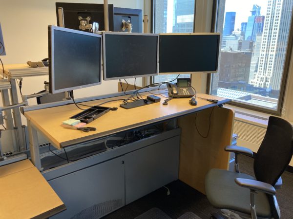 trading desk with 3 monitors adjusted to stand mode