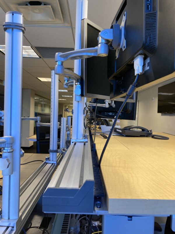 monitor arms attached to adjustable trading desk close up